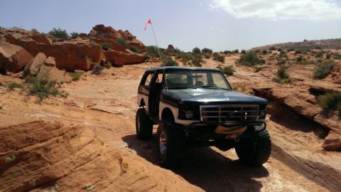 1994 Ford Bronco - Modified Ford Bronco navigates a challenging off-road trail in a desert environment.