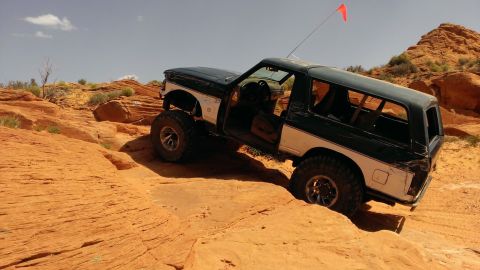 1994 Ford Bronco - This modified SUV is tackling a challenging off-road course with its doors open.