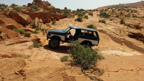 1994 Ford Bronco - Ford Bronco navigating a challenging off-road trail in a desert environment.