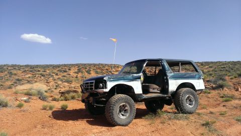 1994 Ford Bronco - This modified Ford Bronco sits in a desert environment under a clear blue sky with a single cloud.