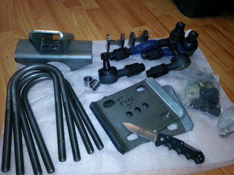 1989 Ford Bronco - Various automotive suspension components are laid out on a white cloth, including U-bolts and tie rod ends.