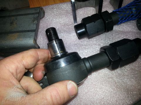 1989 Ford Bronco - A close-up view of a tie rod end being held, with other automotive parts visible in the background.