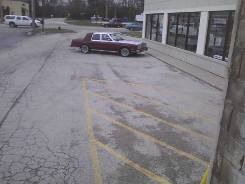 2003 Ford Crown Victoria - A two-tone sedan is parked in a lot next to a building.