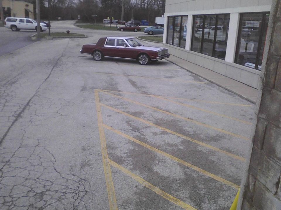 Maroon and white sedan parked in a lot, side view