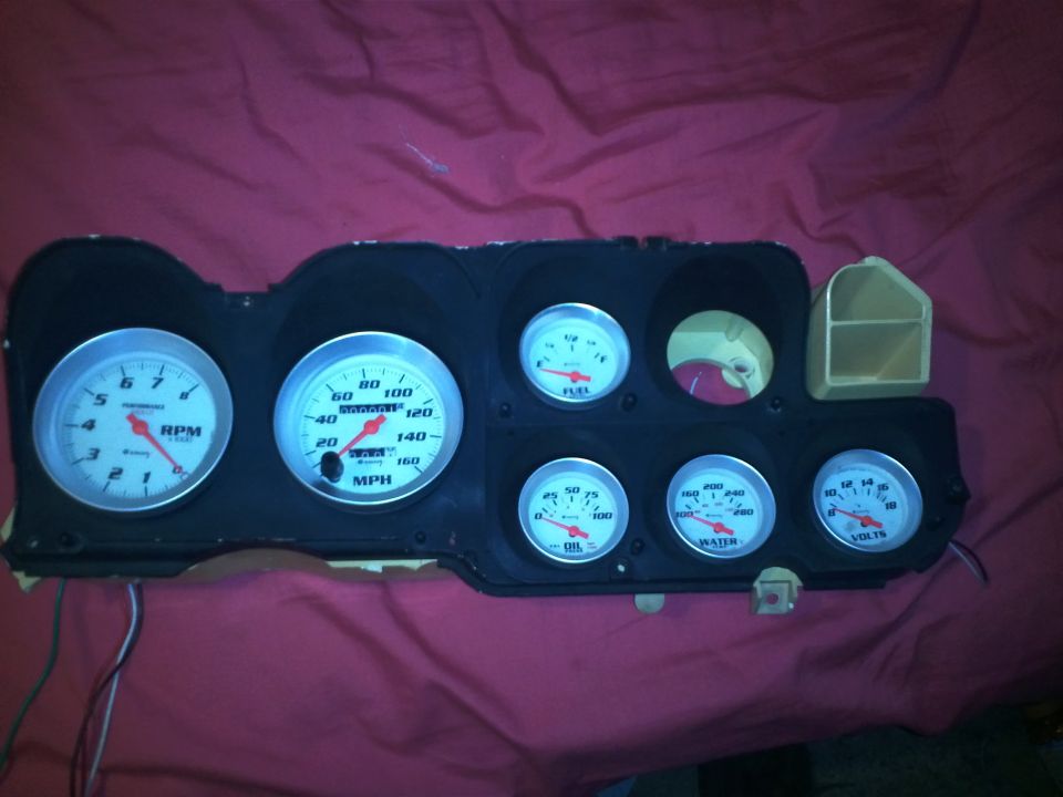 Instrument cluster with RPM, MPH, Fuel, Oil, Water, and Volt gauges against a red fabric background