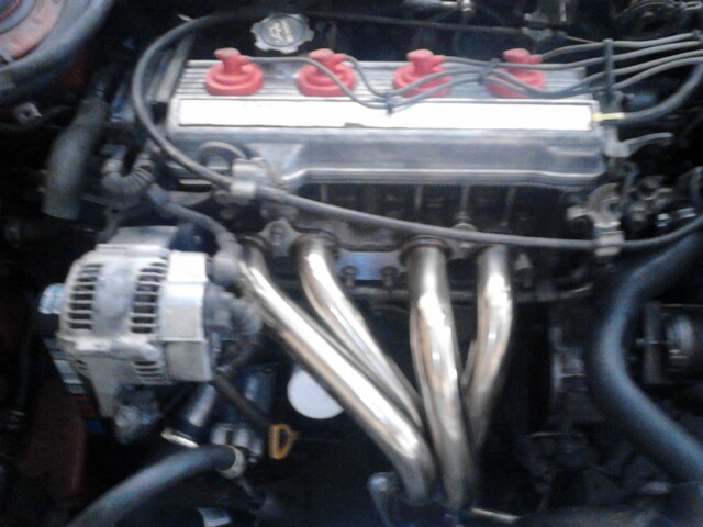 Engine bay showing exhaust manifold, alternator, and spark plug wires