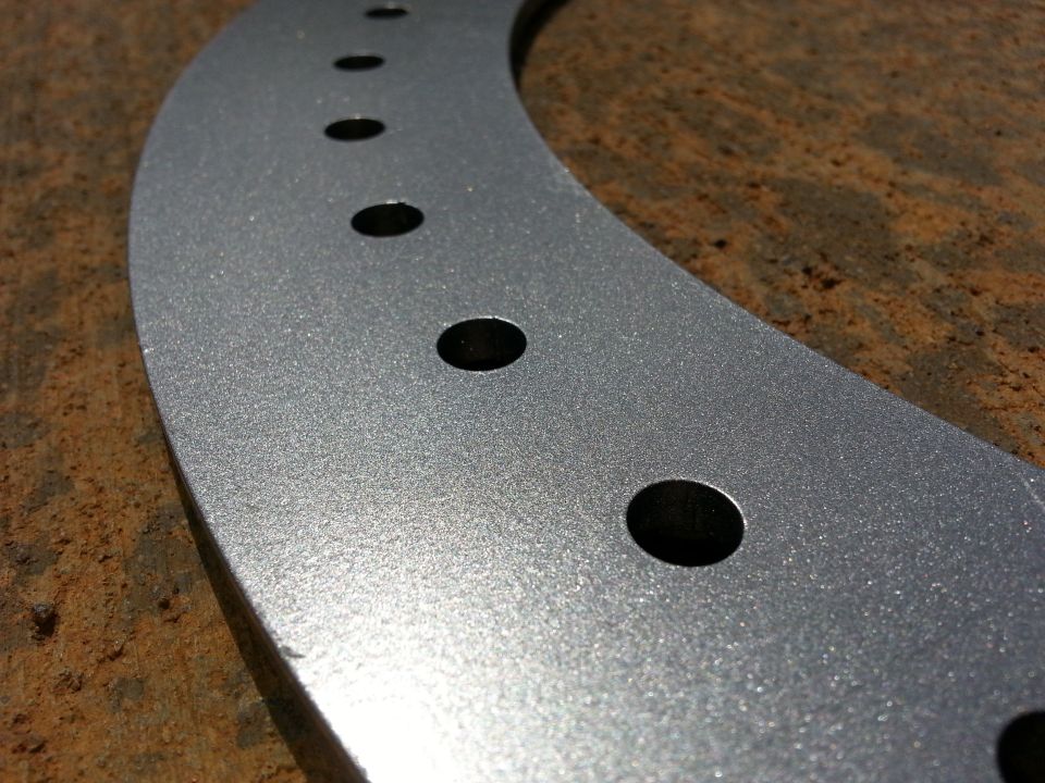 Close-up of a silver wheel spacer with multiple bolt holes