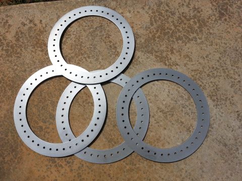 1995 Ford Bronco - Several beadlock rings are laid out on a concrete surface, showing their circular design with numerous perforations.