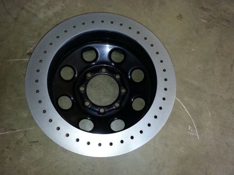 1995 Ford Bronco - This drilled brake rotor features a black center and a silver outer ring with numerous small holes.
