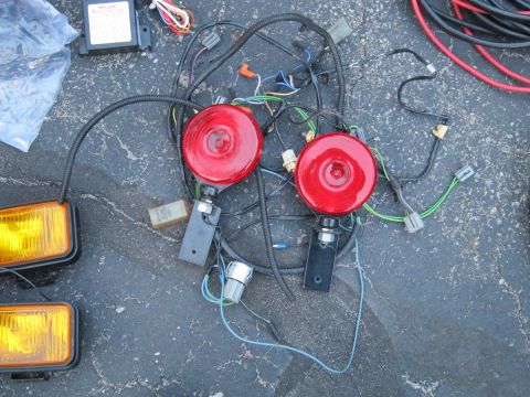 1991 Ford LTD Crown Victoria - A collection of automotive lighting parts and wiring is laid out on asphalt.
