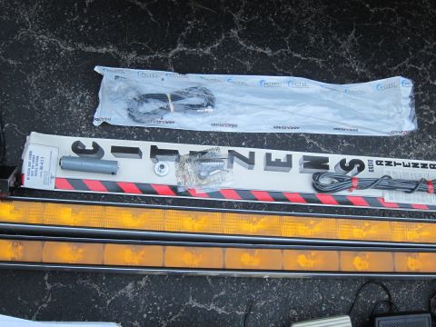 1991 Ford LTD Crown Victoria - Various parts for emergency vehicle lighting and communication equipment are displayed on a dark, textured surface.