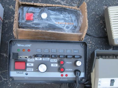 1991 Ford LTD Crown Victoria - A Whelen siren control unit is shown, along with another device in a cardboard box and a speaker.