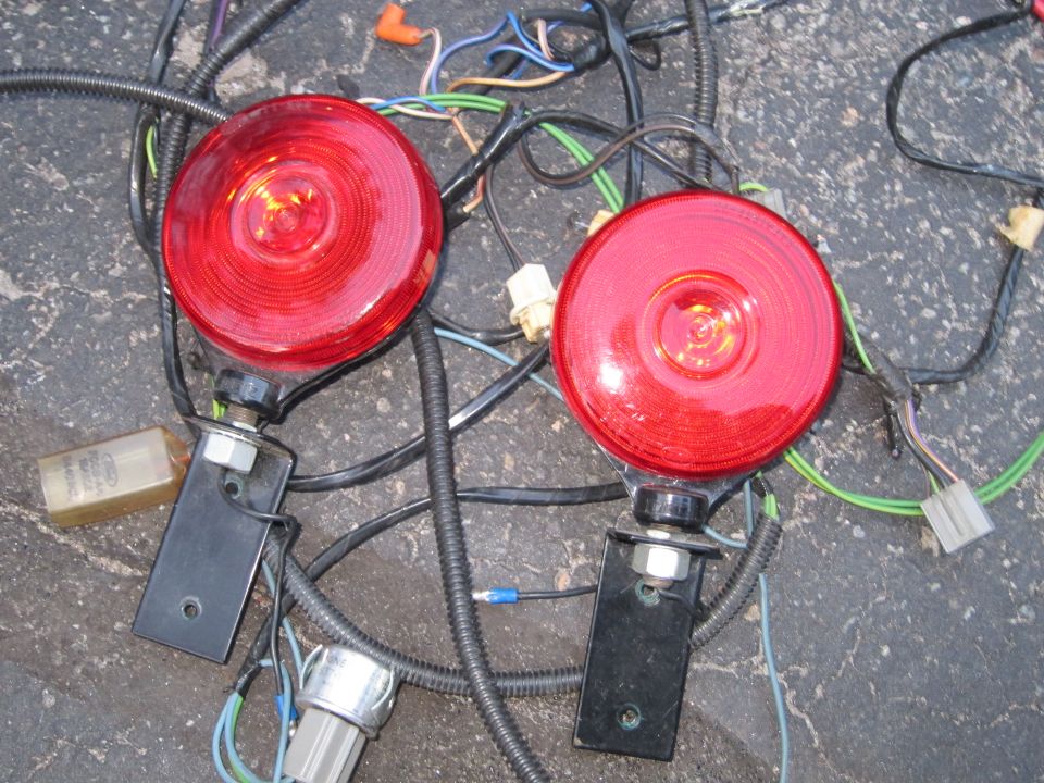 Two red round taillights with black mounting brackets and a complex wiring harness