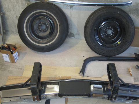 1991 Ford LTD Crown Victoria - Spare tires and a chrome bumper are laid out on the floor, possibly for a restoration project.