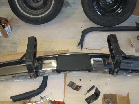 1991 Ford LTD Crown Victoria - A disassembled vehicle bumper and tires are laid out on a concrete floor with tools and parts.