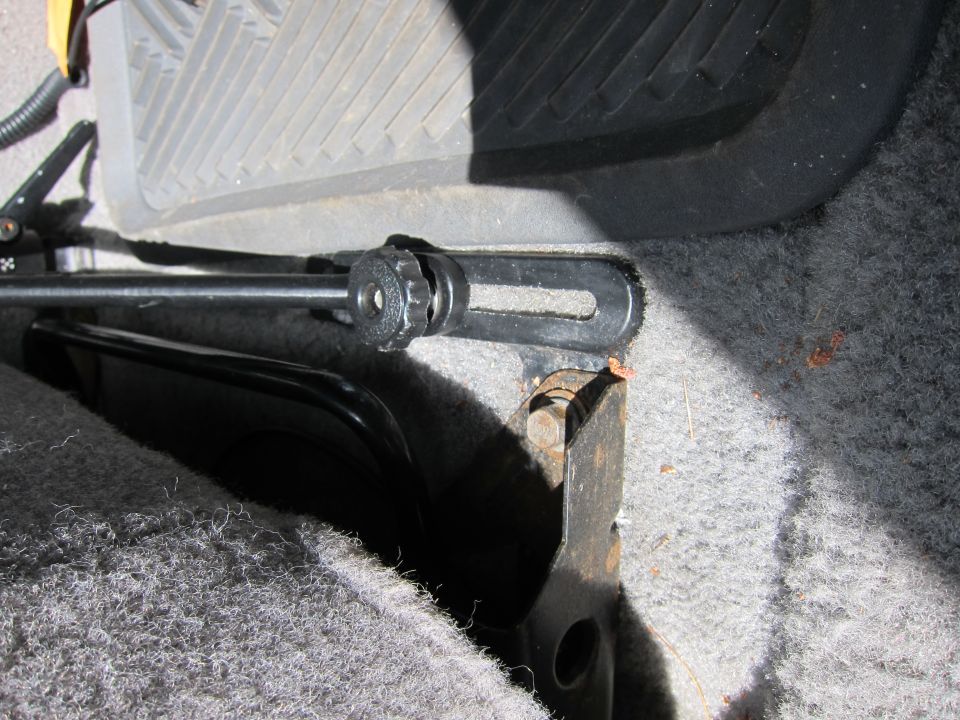 Interior view of a seat adjustment mechanism with a black lever and metal bracket