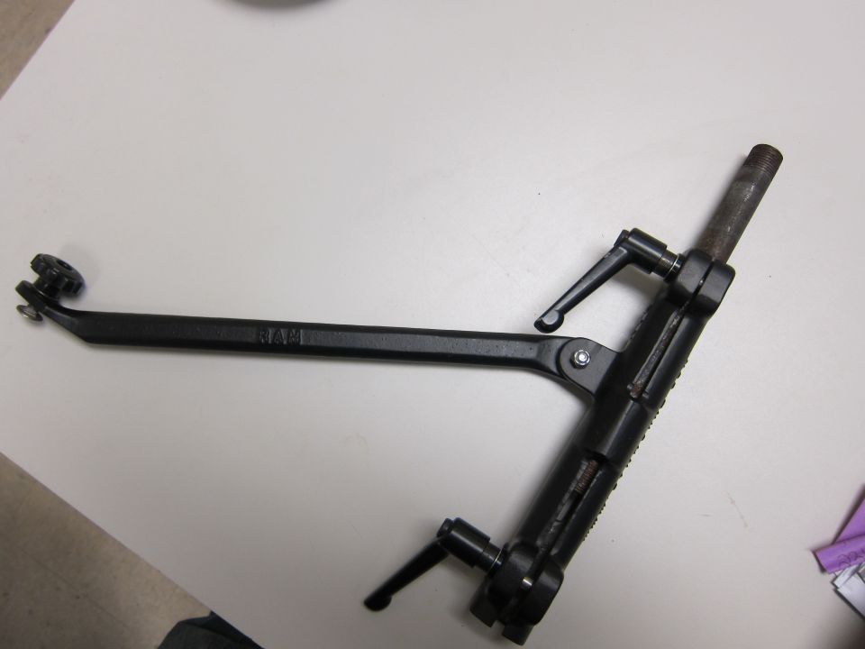 Black metal tool with adjustable arms and knobs, marked "RAM", on a white surface
