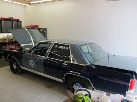 1991 Ford LTD Crown Victoria - Police car with hood open in a garage setting, showing its two-tone paint scheme.