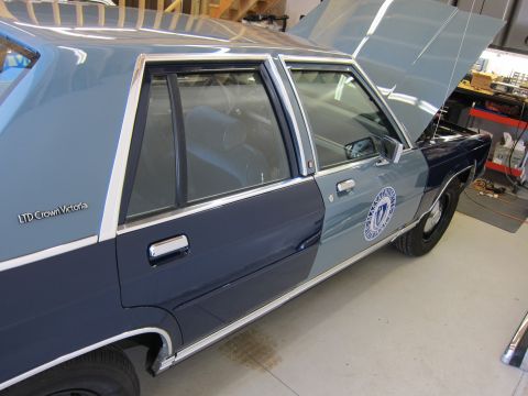 1991 Ford LTD Crown Victoria - This 1991 Ford Crown Victoria LTD police car is shown with its hood open, revealing the engine bay. The vehicle features a distinctive two-…