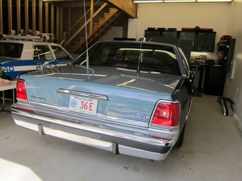 1991 Ford LTD Crown Victoria - A 1991 Ford Crown Victoria LTD is parked in a garage next to a police car.
