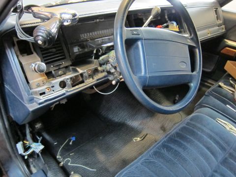 1991 Ford LTD Crown Victoria - The interior of a car shows disassembled dashboard components and blue velour seating.