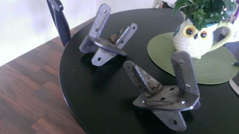 1994 Ford Bronco - Two metal brackets are displayed on a table, with a decorative owl mug holding a plant in the background.
