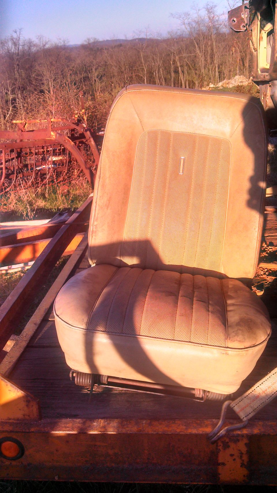 Tan car seat with vertical stitching on the backrest and horizontal stitching on the seat cushion, resting on a trailer