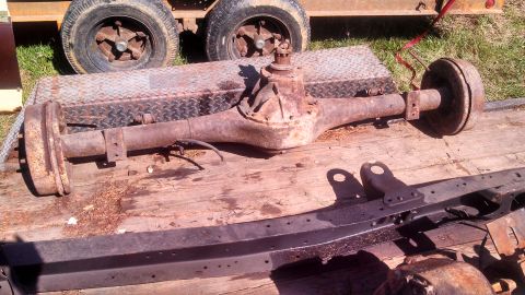 1979 Ford Bronco - A rusty rear axle assembly is shown, likely a part from a vehicle, resting on a wooden surface.