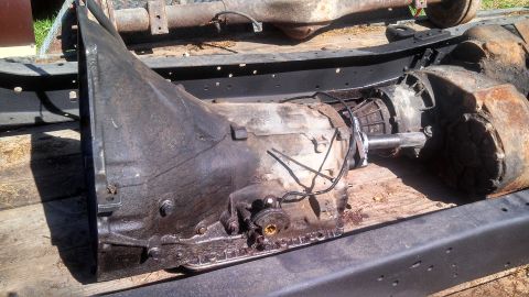 1979 Ford Bronco - A greasy automatic transmission and transfer case are shown disassembled from a vehicle.