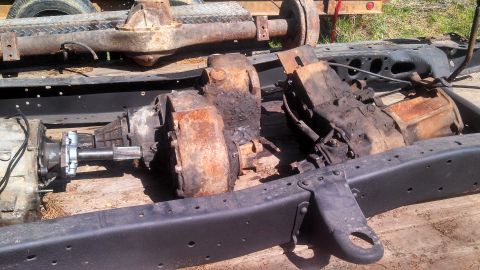 1979 Ford Bronco - Drivetrain parts, including a transfer case and transmission, are shown disassembled on a black frame.