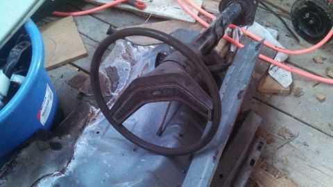 1979 Ford Bronco - Interior parts of a vehicle, including a steering wheel and dashboard section, are scattered on a wooden floor.