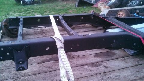 1979 Ford Bronco - A bare truck frame, likely for parts, is shown strapped down on a wooden surface.