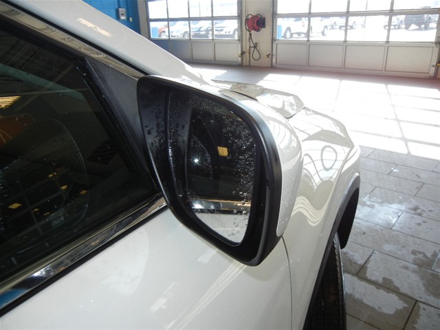 White SUV side mirror with water droplets, showing reflection of garage interior