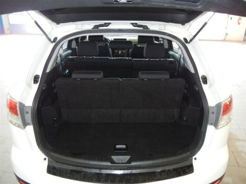 2008 Mazda CX-9 - The rear cargo area of a white SUV is shown with the trunk open, revealing the seats and storage space.