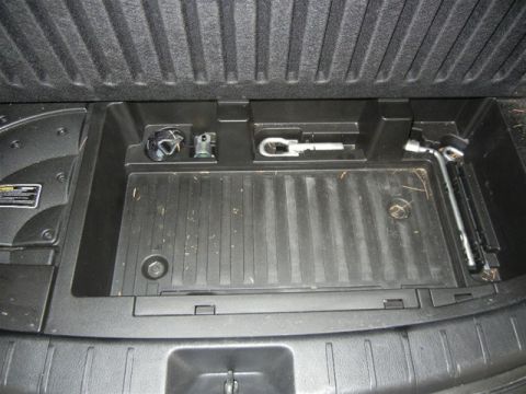 2008 Mazda CX-9 - The cargo area of a vehicle contains a jack, lug wrench, and tow hook stored in compartments.