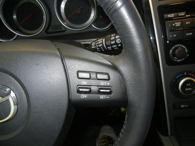Interior shot of a 2008 Mazda CX-9 showing the steering wheel controls, dashboard gauges, and center console