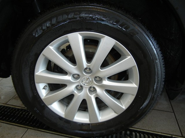 Close-up of a silver 5-spoke wheel with a Mazda logo, fitted with a Bridgestone tire