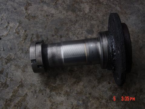 1987 Ford Bronco - A close-up view of a vehicle spindle, likely for a wheel bearing assembly, is shown on a textured surface.