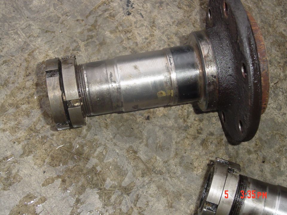 Axle spindle and hub assembly disassembled on concrete floor showing bearing surfaces