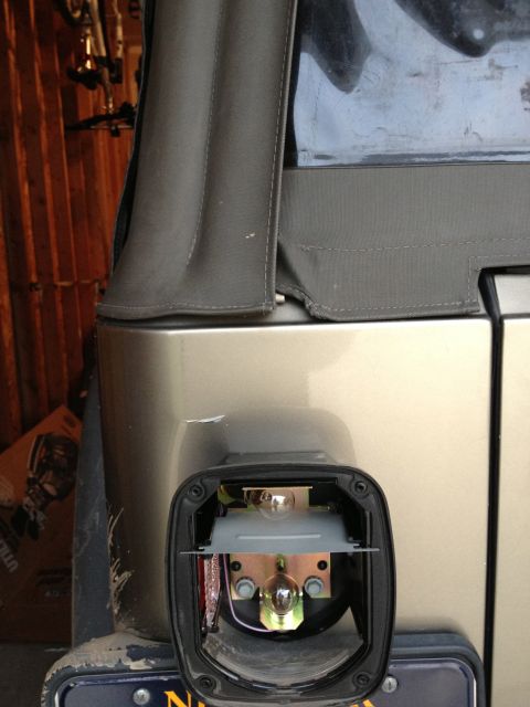 2005 Jeep Wrangler - Close-up of a disassembled tail light on a tan Jeep Wrangler, revealing internal components and wiring.
