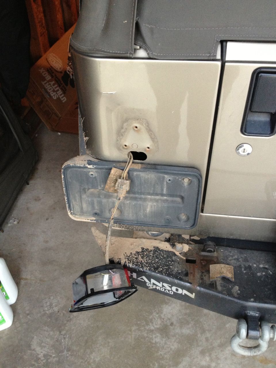 Gold Jeep Wrangler rear bumper with detached taillight and license plate bracket