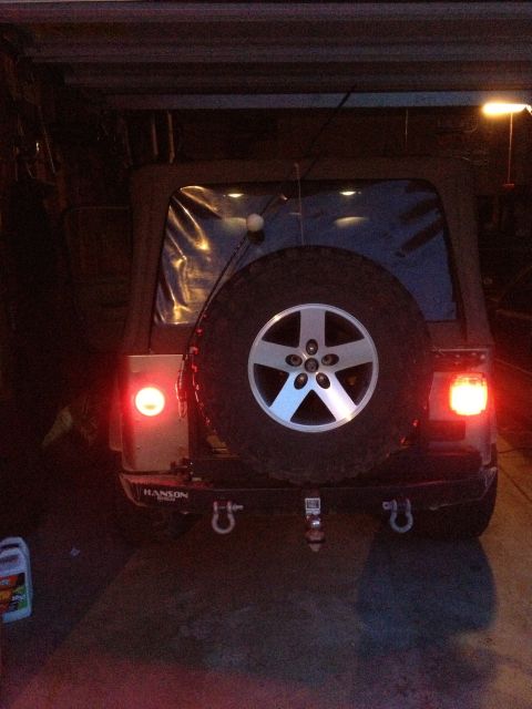 2005 Jeep Wrangler - The rear of a 2005 Jeep Wrangler is visible, a spare tire and illuminated taillights.