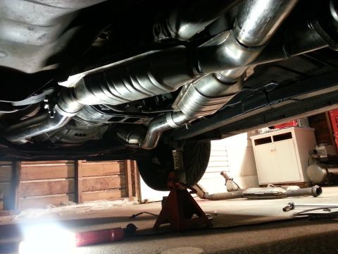 1995 Ford Mustang - The exhaust system of a vehicle is shown from underneath, supported by jack stands.