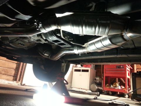 1995 Ford Mustang - The underside of a vehicle displays its exhaust system, including catalytic converters and an X-pipe, while being serviced.