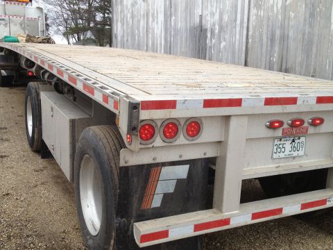 2003 Peterbilt 379 - This flatbed trailer features reflective tape and multiple brake lights on its rear.