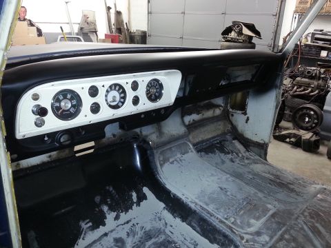 1967 Ford F-100 - Interior view of a 1967 Ford F-100 dashboard and floor, showing gauges and unfinished surfaces.