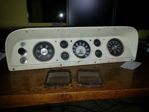 1967 Ford F-100 - A vehicle's instrument cluster with various gauges is displayed on a wooden surface.