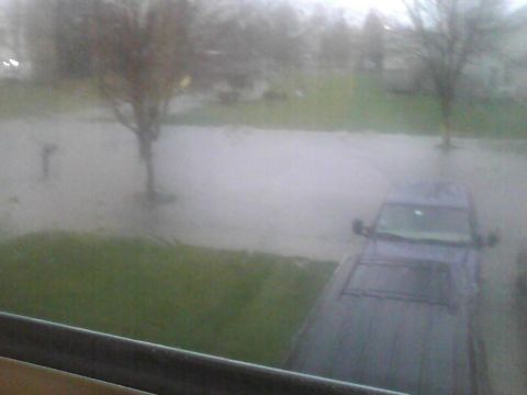 2003 Ford Crown Victoria - A dark SUV is partially submerged in a flooded street during inclement weather.