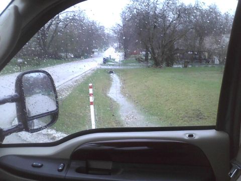 2003 Ford Crown Victoria - The view from the driver's seat shows a rainy day with water on the road and grass.