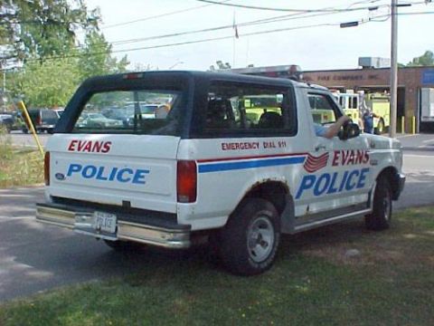 1994 Ford Bronco - This police SUV has 'EVANS POLICE' and 'EMERGENCY DIAL 911' text visible on its exterior.